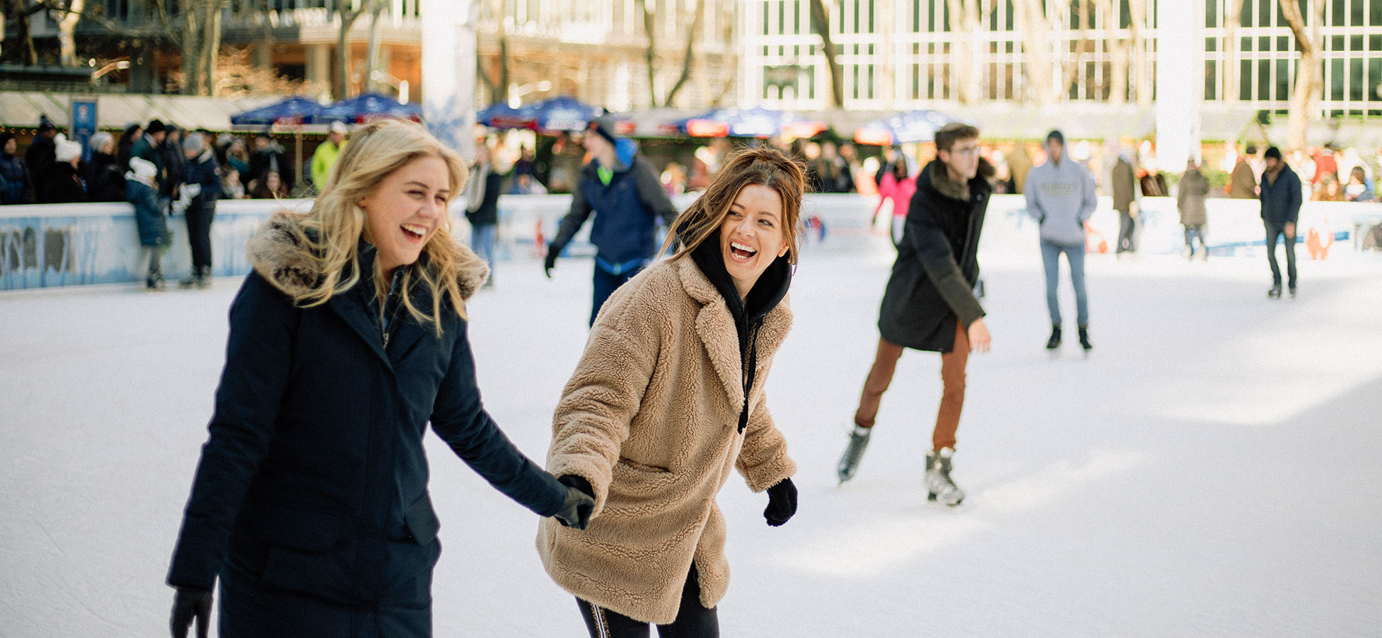 two young women ice skating at the rink at rockefeller center in new york city